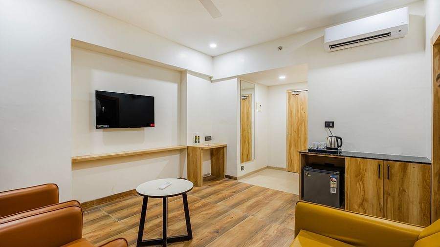 Lemonridge Hotels, KPHB | Hotel room with a TV mounted on the wall, a small table, and a chair. Entertainment options.